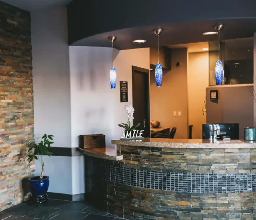The Smiles by Goh reception — stone counter, warm pendant light, an orchid on the desk