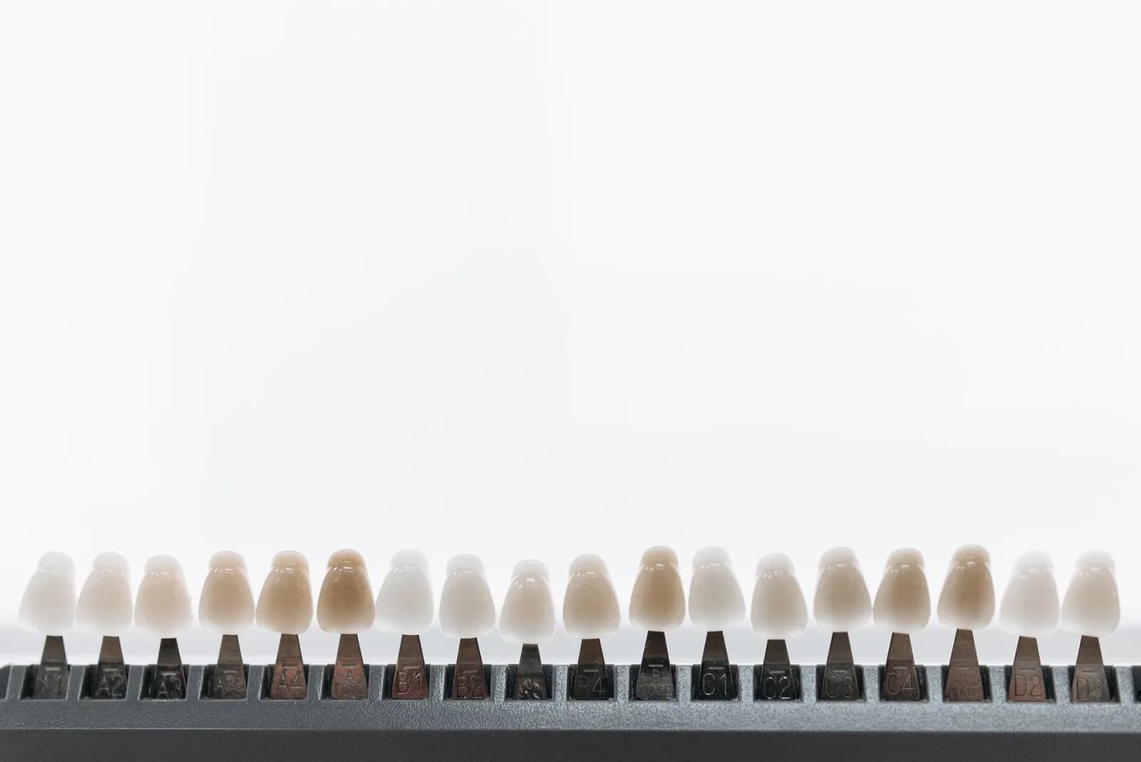 A dental shade guide — a row of tooth-coloured tabs graded from light to dark